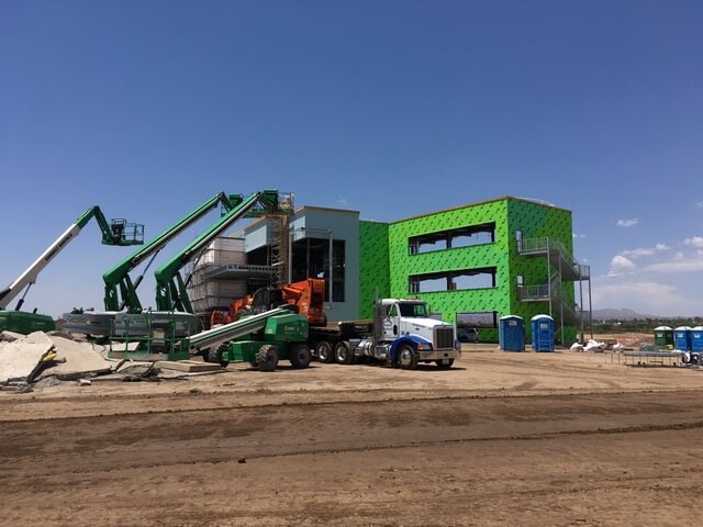Cranes are lifting roofing materials onto a new roof construction project in preparation for a commercial roofing installation